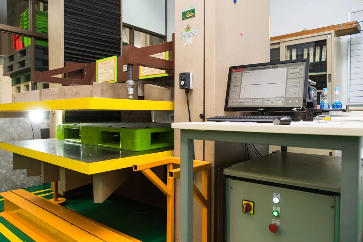 พาเลทพลาสติกสีเขียวในเครื่องทดสอบรับแรงกด Compression Test ของโรงงานศรีไทย พร้อมจอแสดงกราฟแรงกด