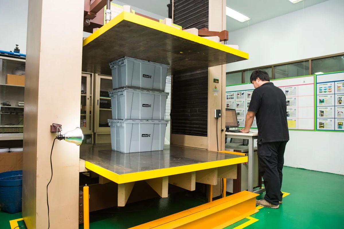 เจ้าหน้าที่ QC ทดสอบแรงกดลังพลาสติกที่วางซ้อน 3 ชั้น ในห้องแล็บโรงงานศรีไทย